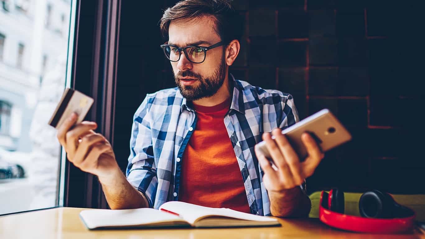 joven sosteniendo celular y tarjeta de crédito en hot sale