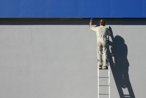 persona pintando pared exterior de azul