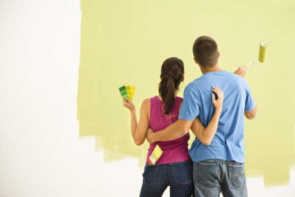 pareja pintando pared amarilla